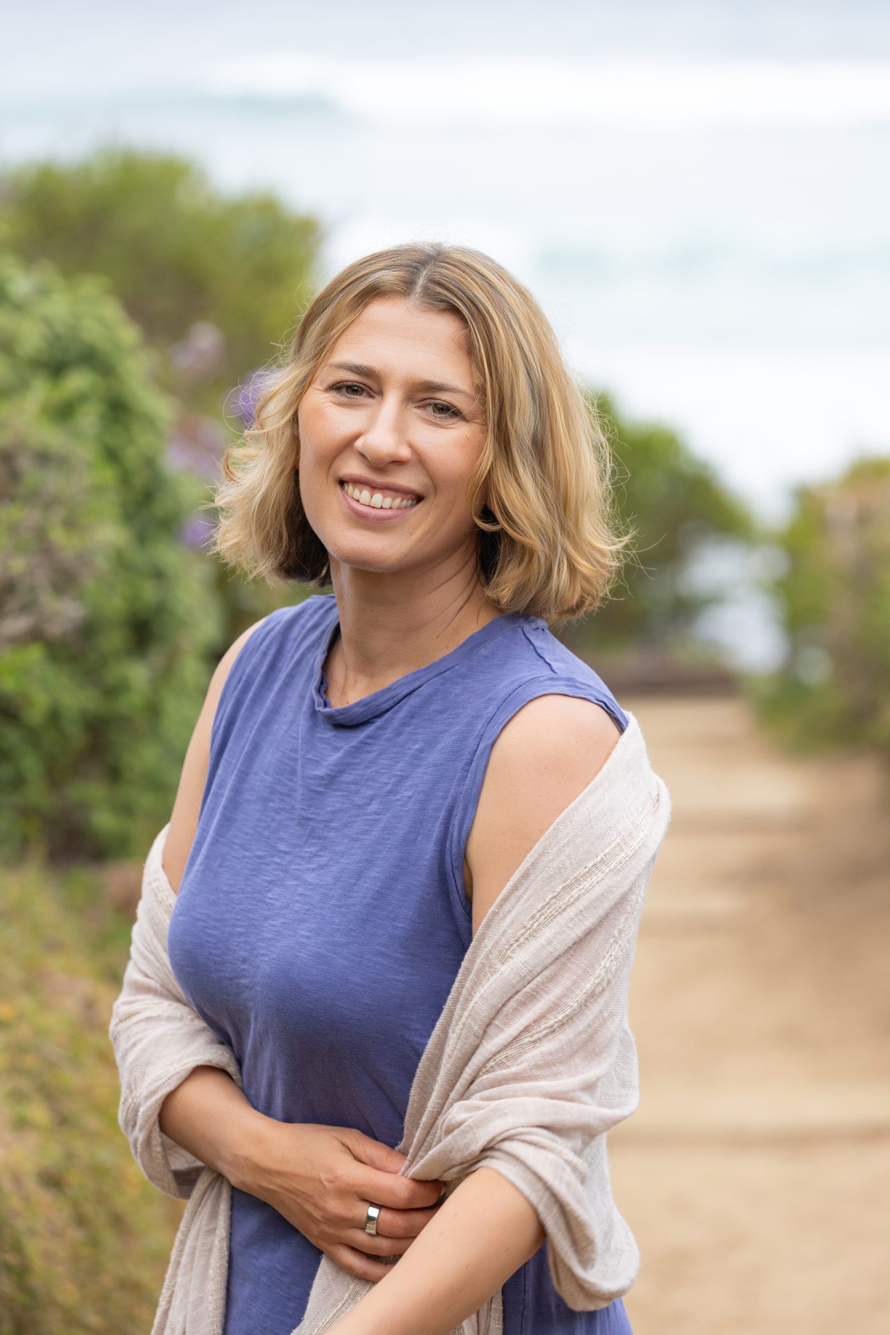 Vera McGrath, LMFT, standing outdoors on a tree-lined path in Carlsbad